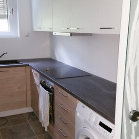 Moderne Einbauküche mit Holzfronten, Waschmaschine, Cerankochfeld und Hängeschränken.