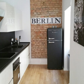 Moderne Berliner Küche mit Backsteinwand, Retro-Kühlschrank und stilvollem Design.
